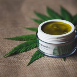 CBD salve on cannabis leaf on brown table